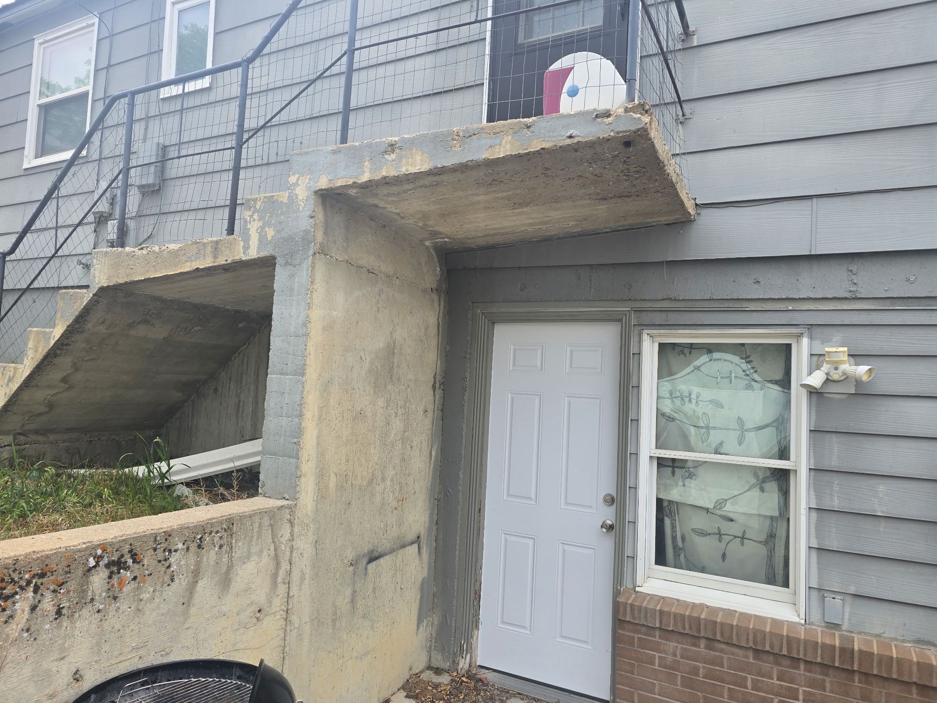 Exterior view of a building with concrete stairs, a door, and a window.