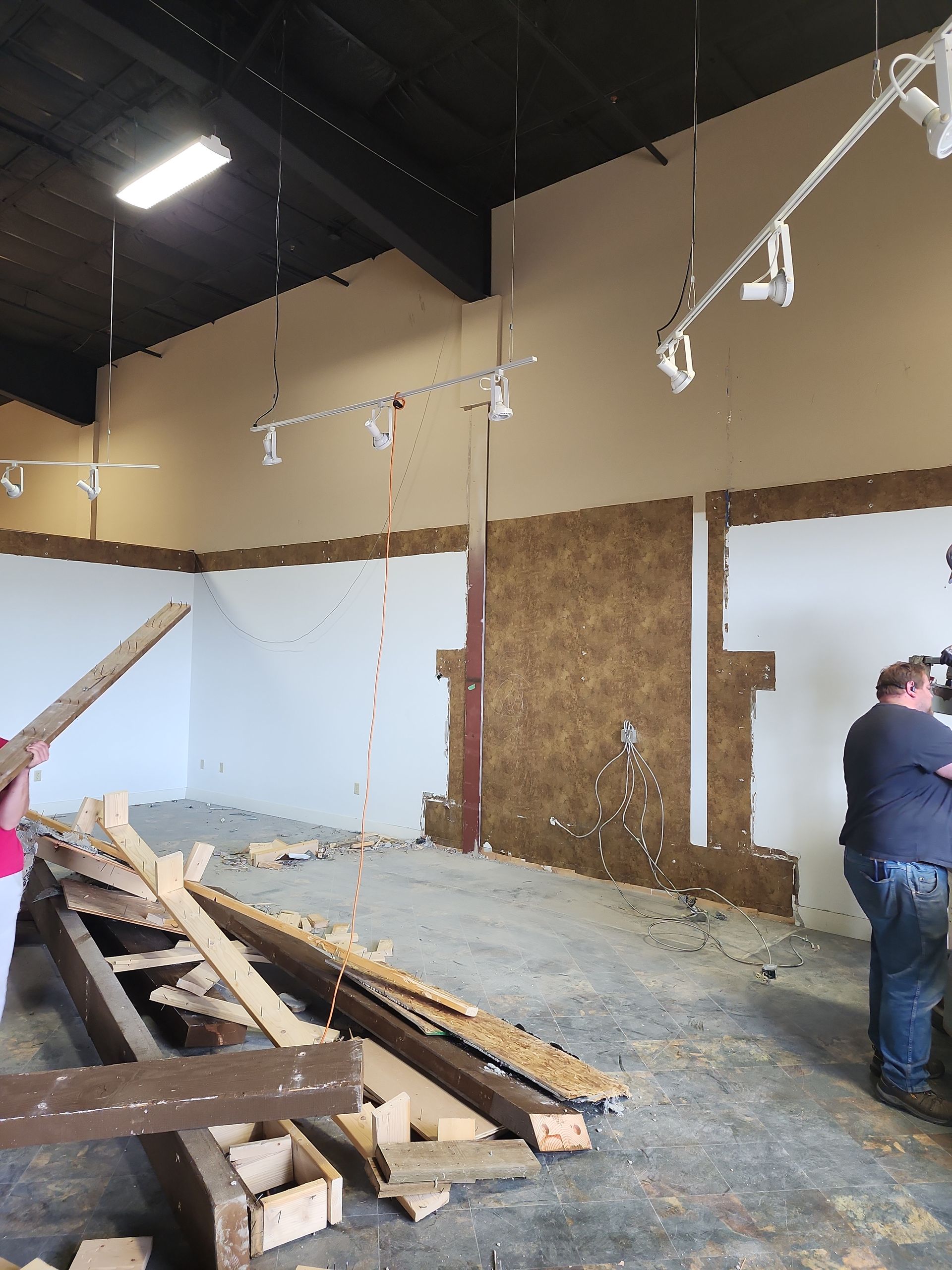 Interior demolition in progress: person, exposed wall sections, debris on floor.