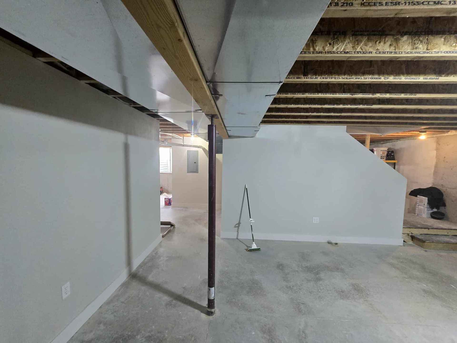 Basement interior with support beam, walls, and unfinished concrete floor.