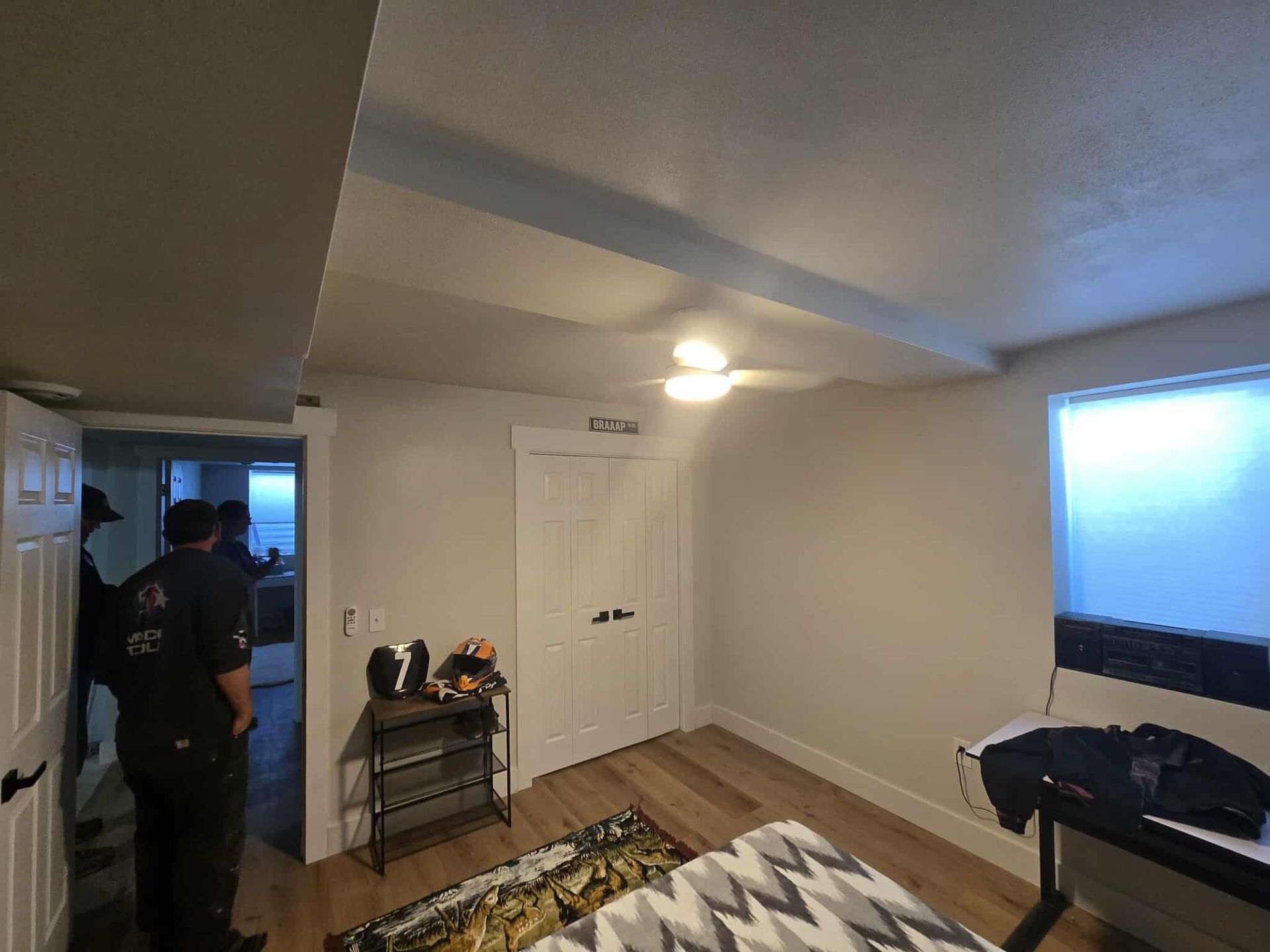 Bedroom with a closet, window, and a bed; two people are visible in the doorway.