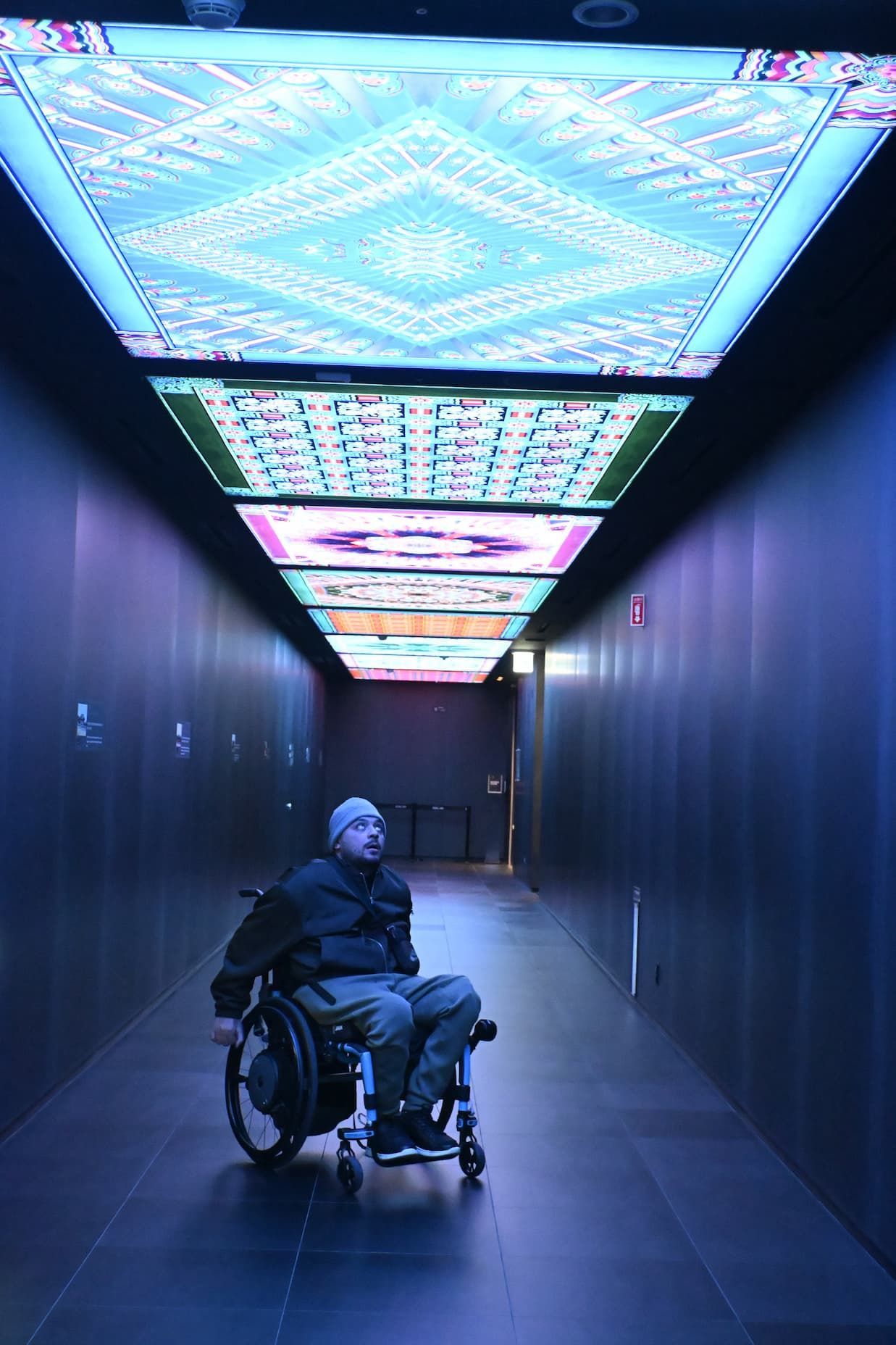 A person in a wheelchair is standing in a hallway.