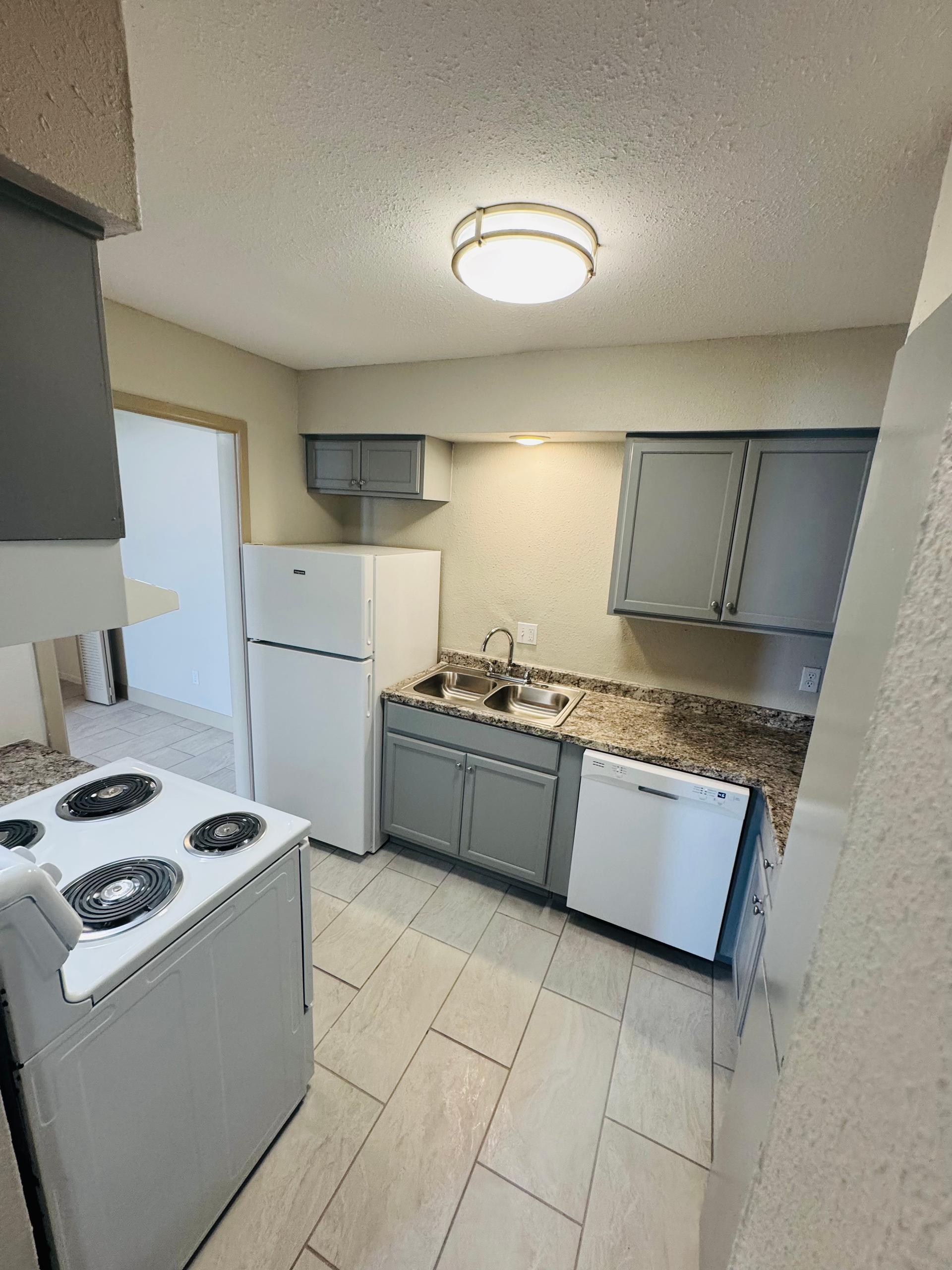 Kitchen with gray cabinets, white appliances, beige tile floor, and a light fixture.
