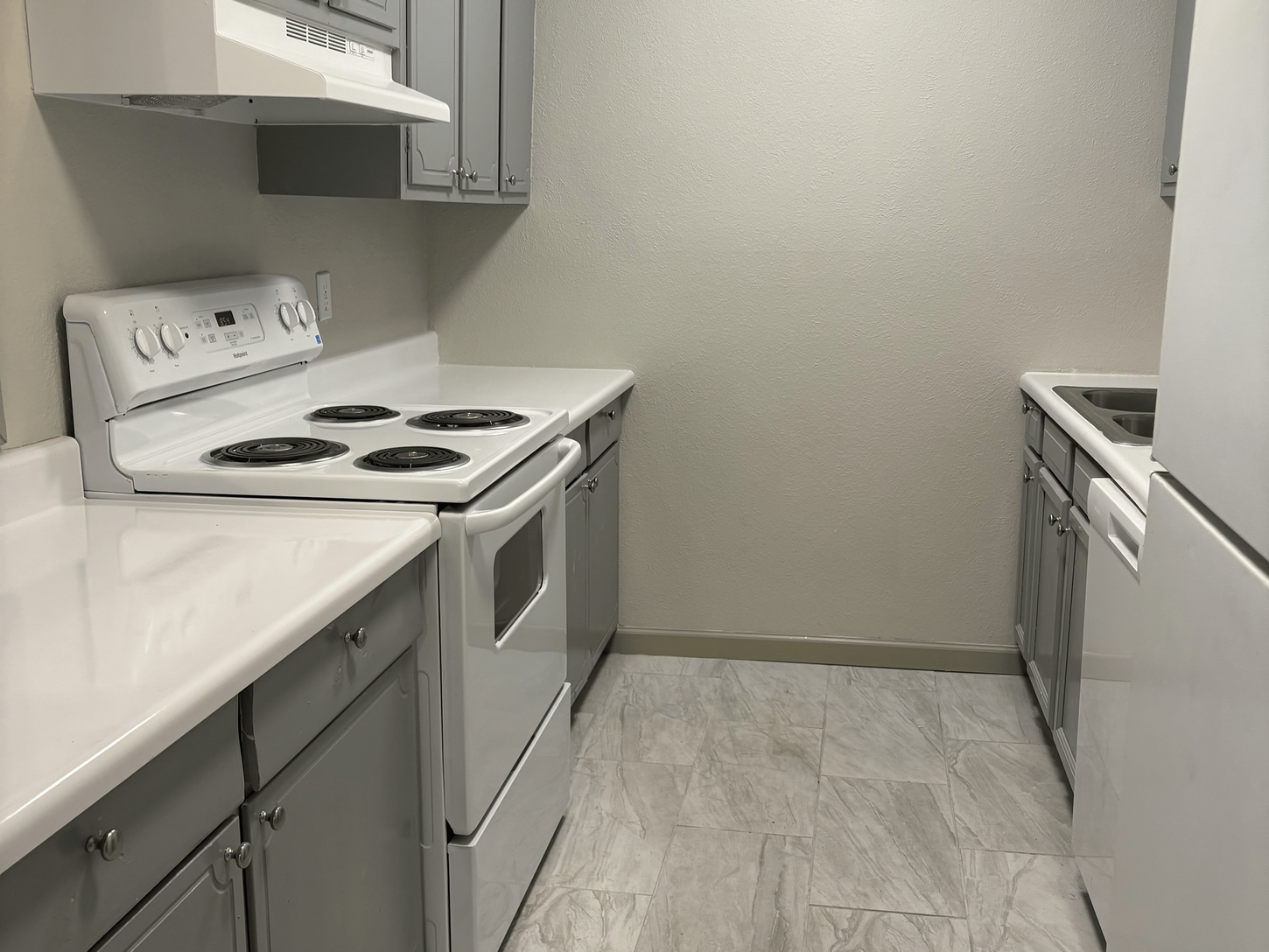 Kitchen with white appliances, beige tile floor 