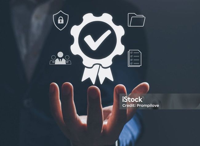 A hand holds a glowing white icon representing quality assurance, surrounded by symbols for security, people, and files.