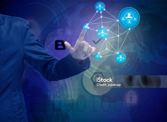 A person in a blue suit touches a glowing digital network of connected user icons against a blue, tech-themed background.