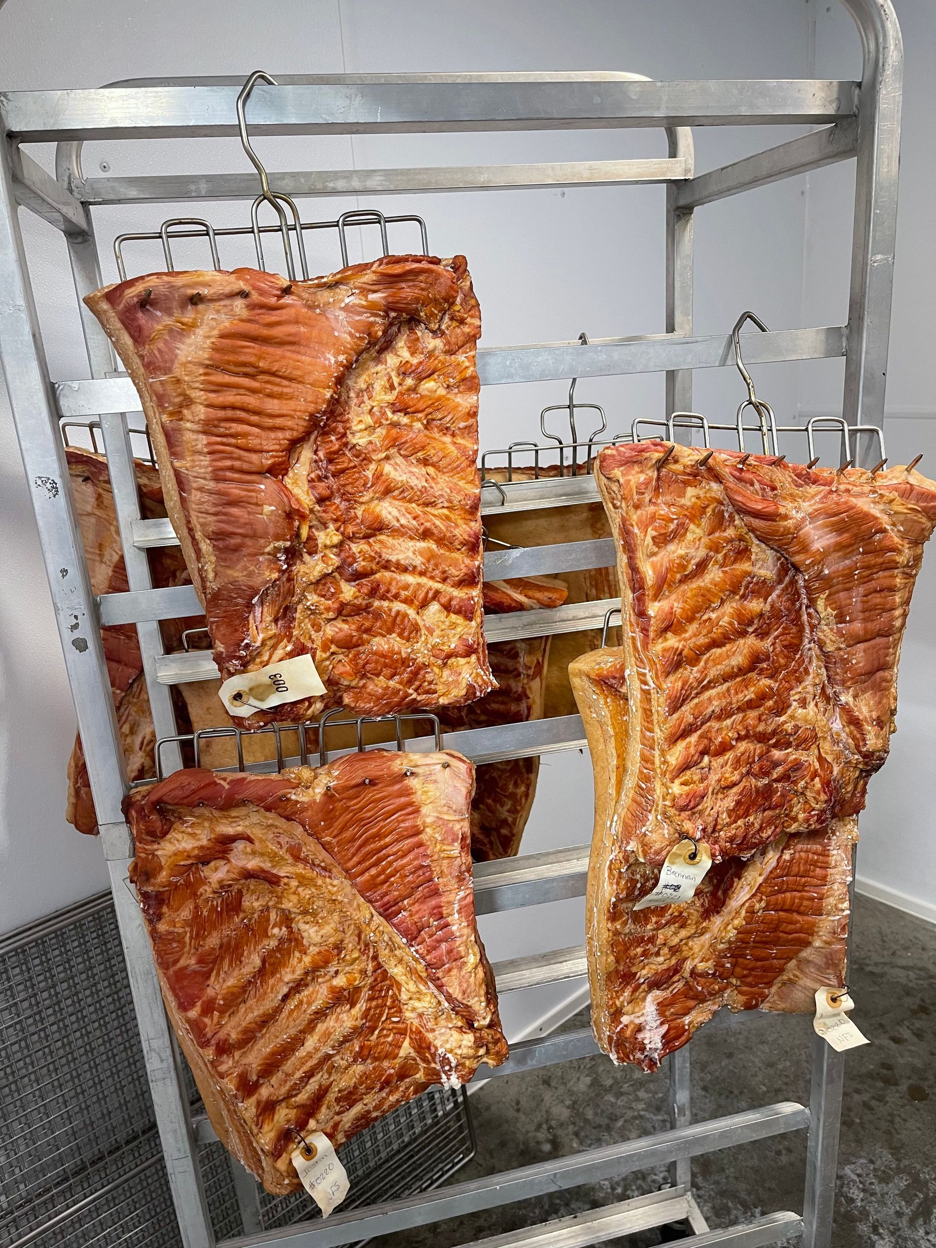 A rack of meat hanging from hooks in a room.