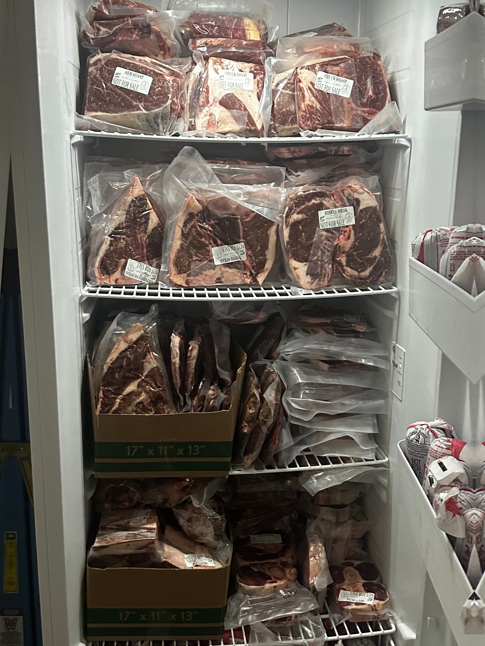A refrigerator filled with lots of meat and boxes.