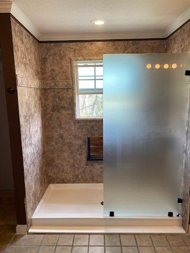 A bathroom with a walk in shower and a window.