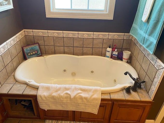 A bathroom with a jacuzzi tub and a window.