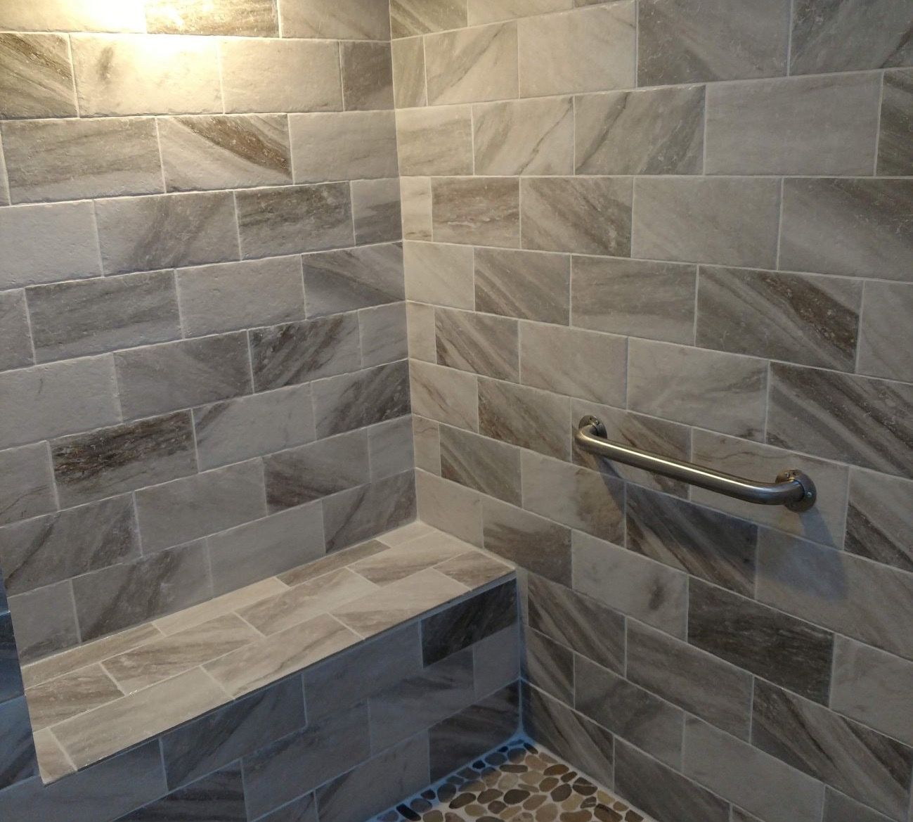 A bathroom with marble tiles and a hand rail