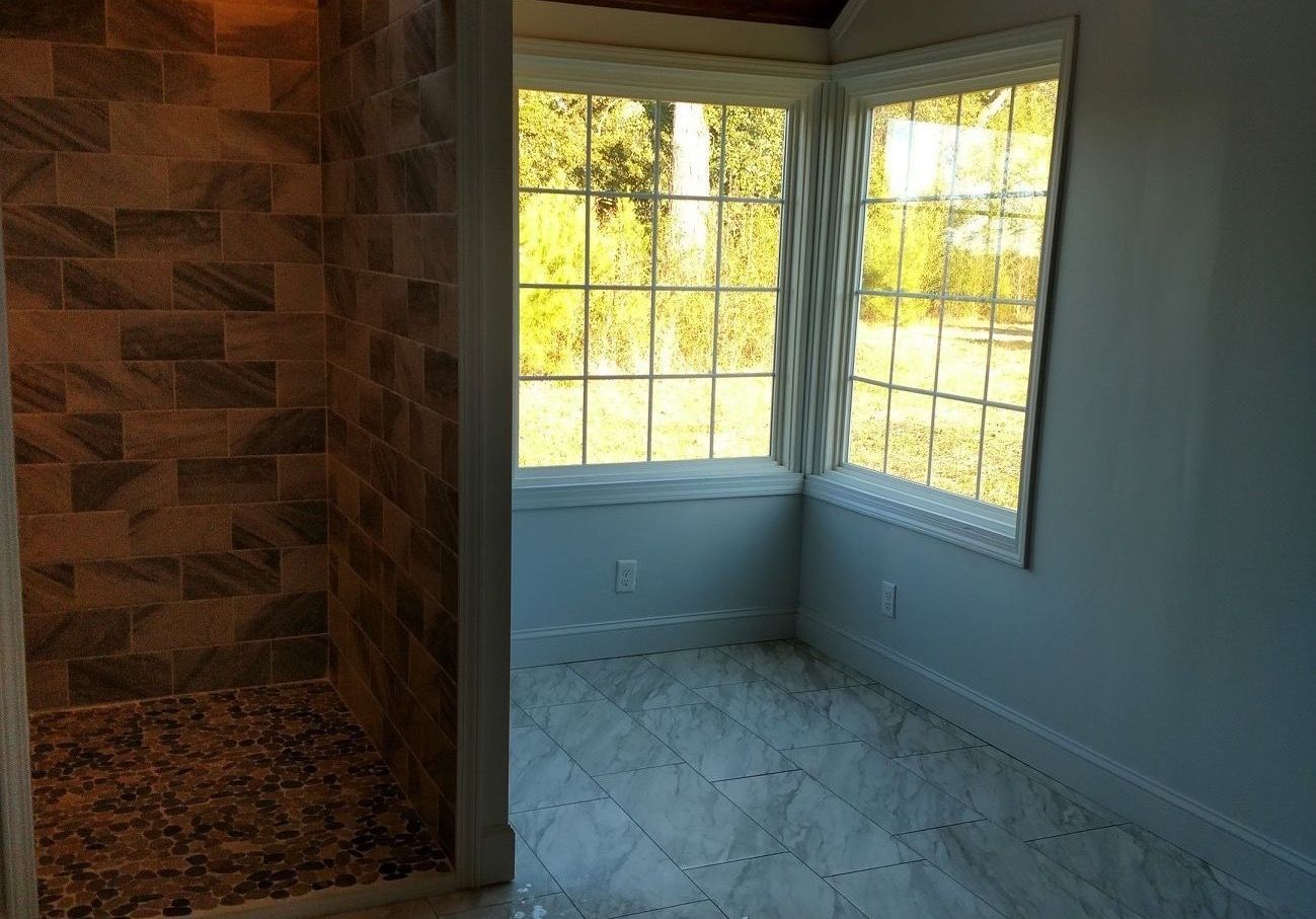 A bathroom with a walk in shower and a window.