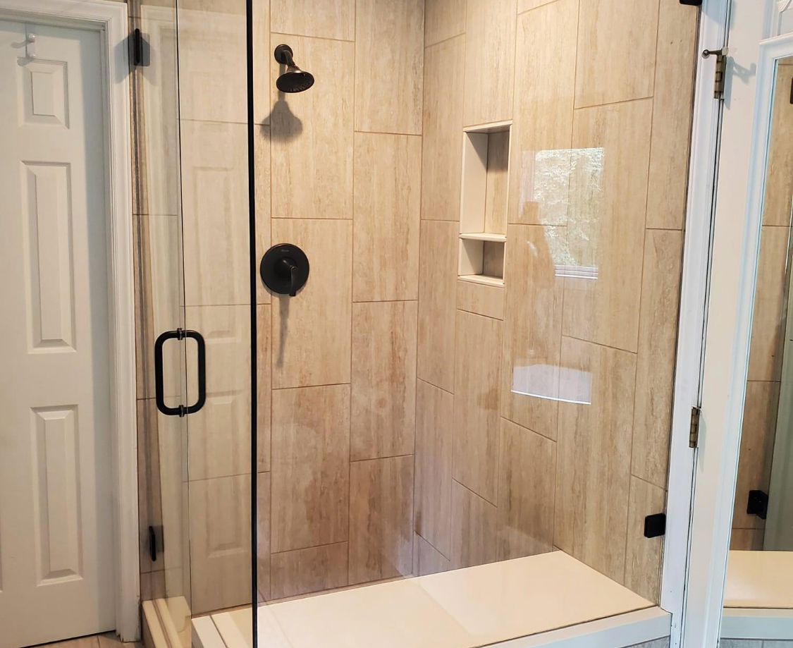 A bathroom with a walk in shower with a glass door.