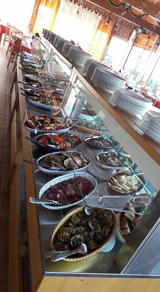 Buffet con una lunga esposizione di piatti vari, in un ristorante.