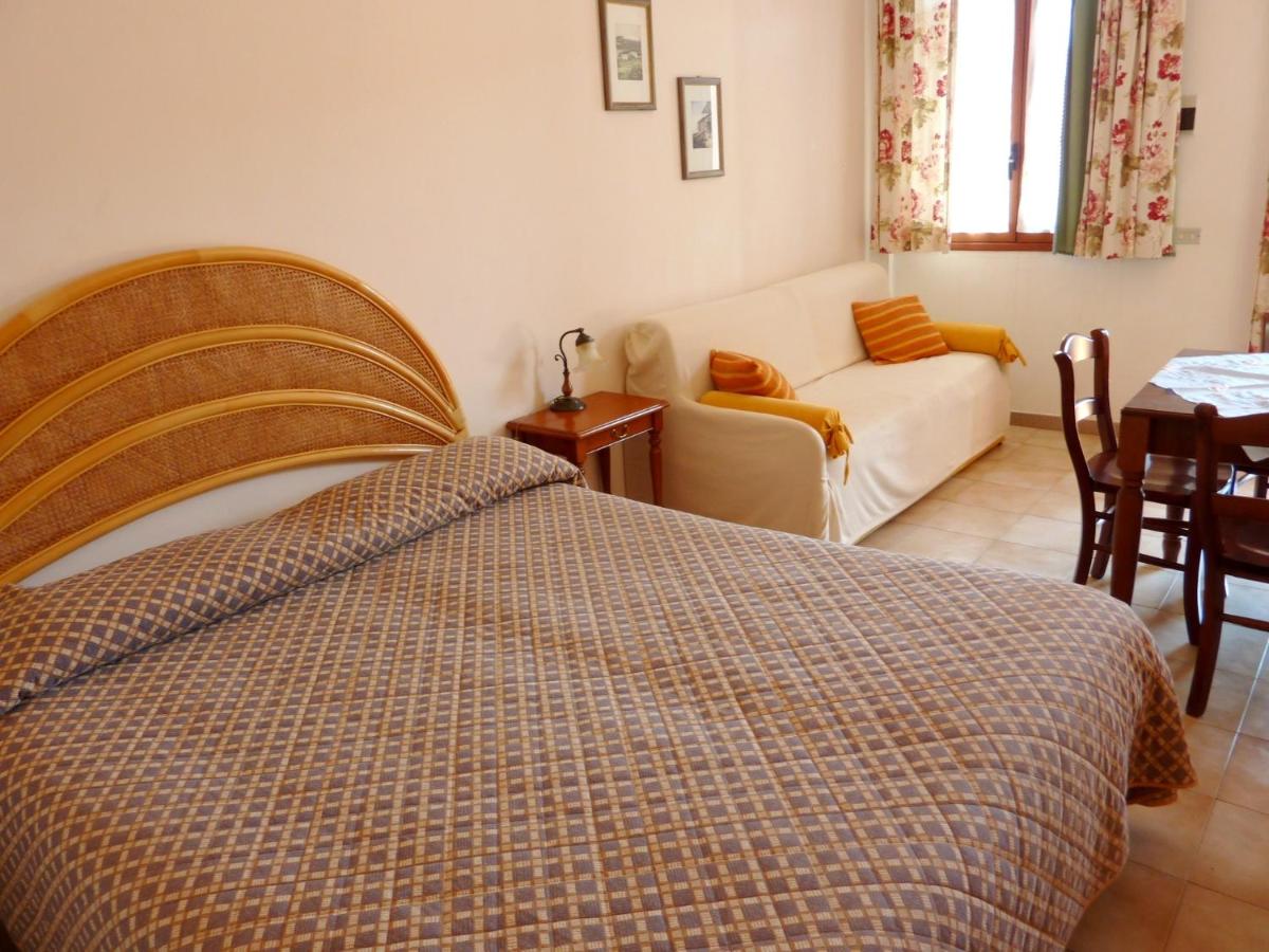 Camera da letto con letto, divano, tavolo da pranzo e finestra. Colori chiari, arredamento semplice.