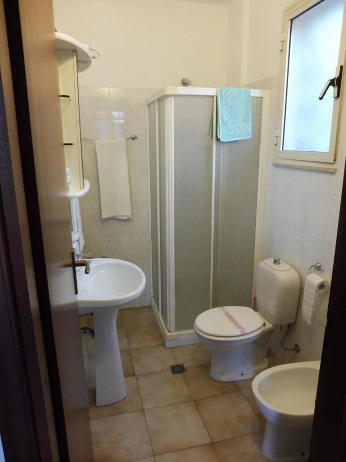 Piccolo bagno con doccia, WC, bidet e lavandino. Asciugamani appesi. La stanza è illuminata.