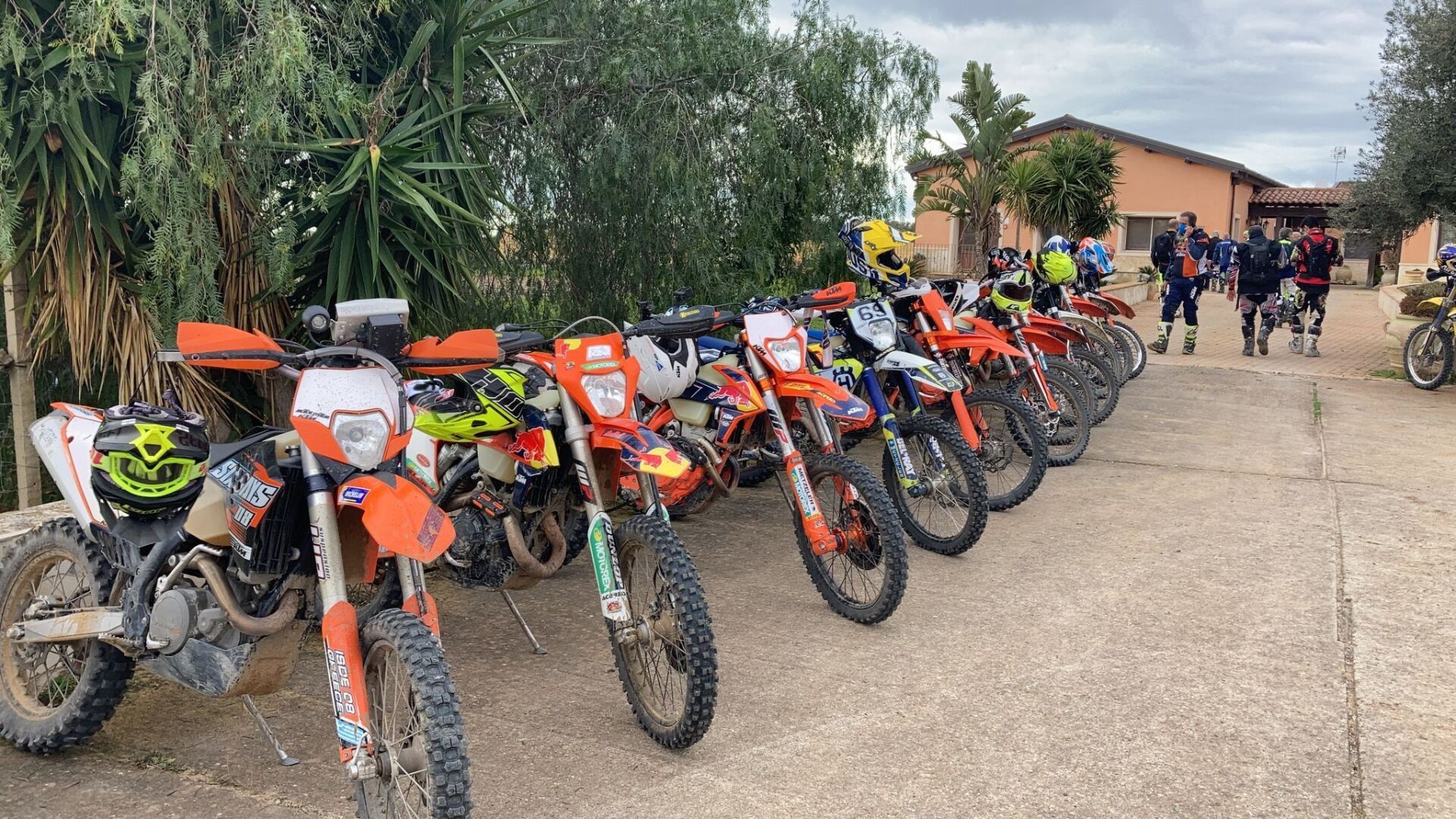 Motociclisti in fila su una strada con le loro moto da cross arancioni, pronti per un giro.