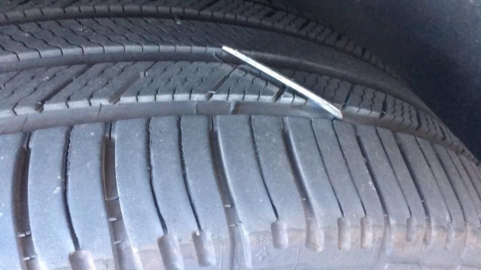 Close-up of a tire with a metal object embedded in the tread.