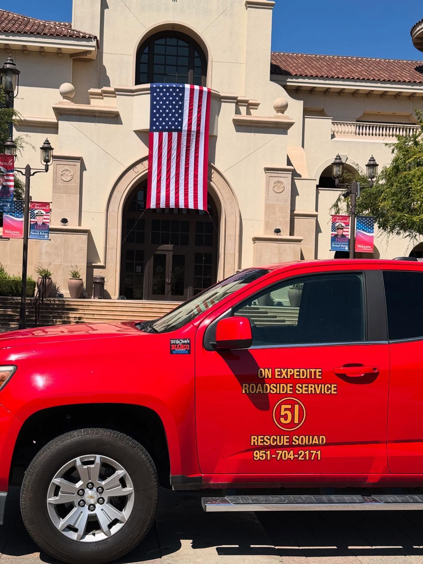 Red fire truck in front of a building with a US flag; 
