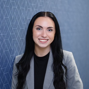 Smiling woman (Olivia Blackford) in a gray blazer against a blue patterned background.