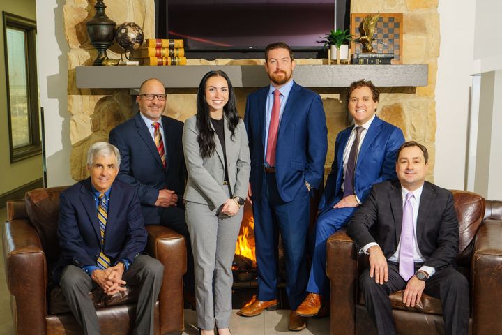 Group of six professionals posing in a in the front office of the SYT Law Firm.