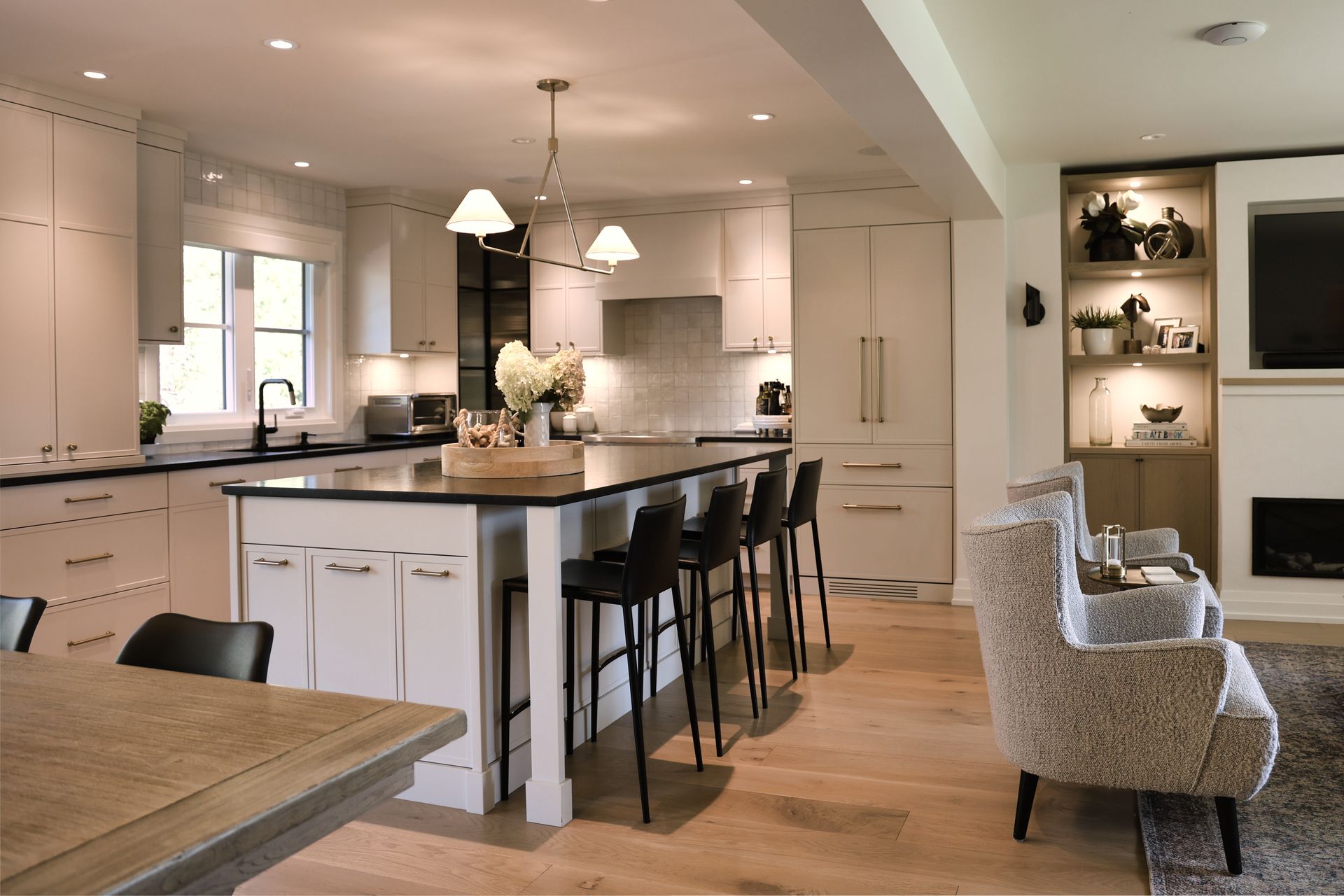 Modern kitchen with white cabinets, dark island countertop, and black bar stools.