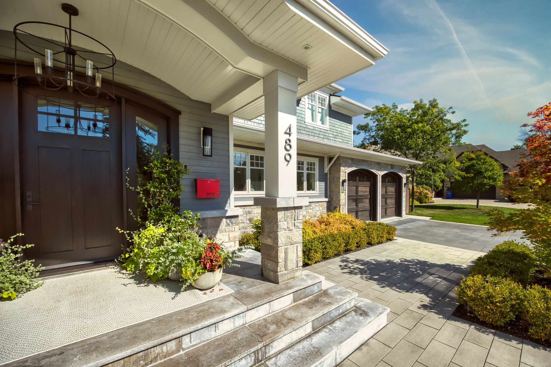 Entrance to a two-story home with gray siding, stone accents, and a red mailbox.