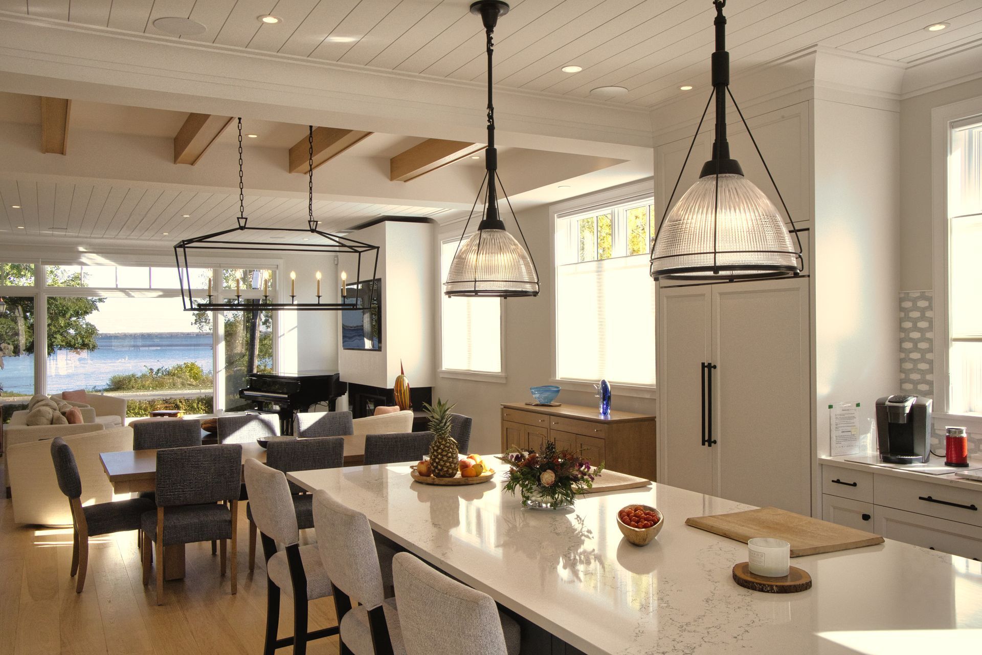 Bright kitchen with island, pendant lights, dining area, and ocean view.