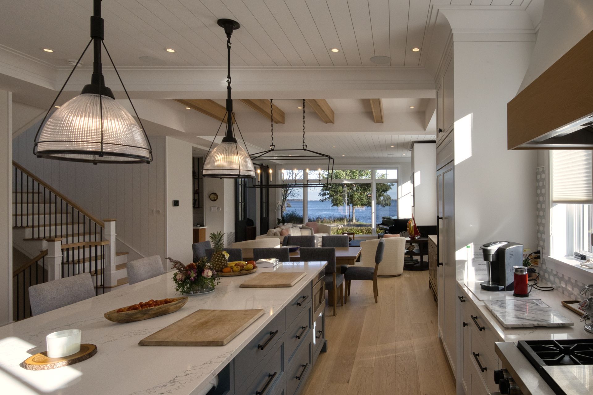 Spacious modern kitchen with island, pendant lights, and view to dining area and water.