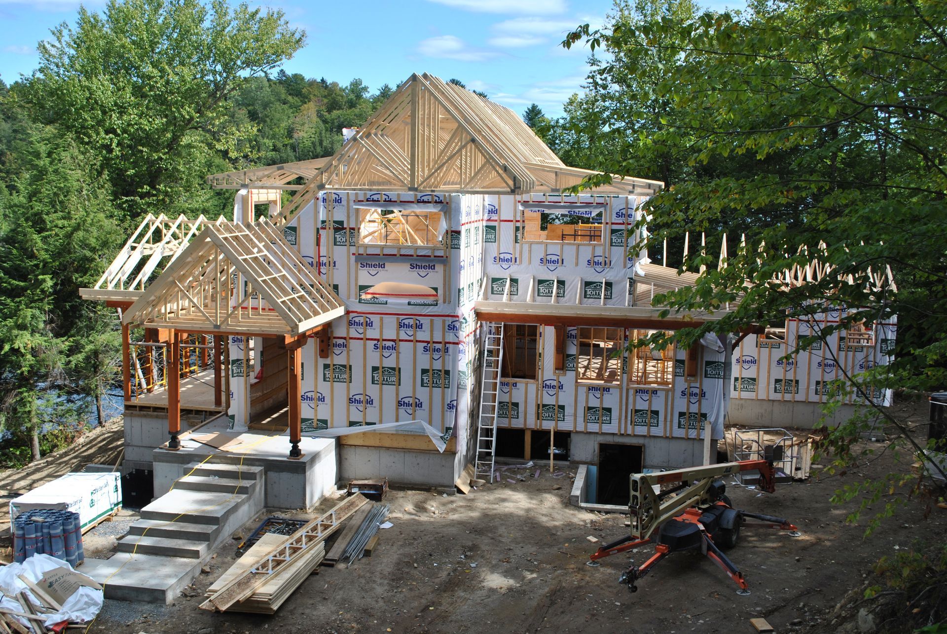 House under construction, wood frame with exposed beams, siding installed.