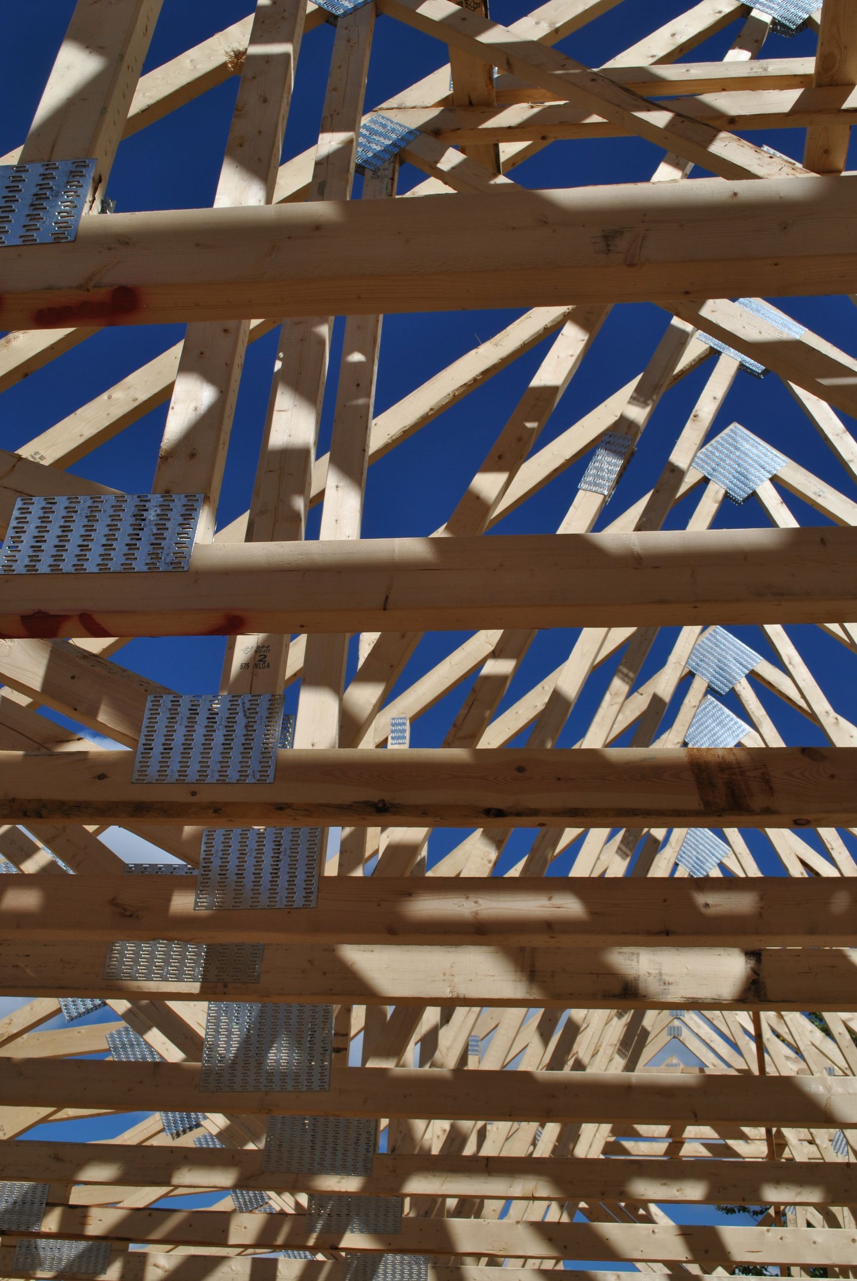 Wooden roof trusses against a bright blue sky.