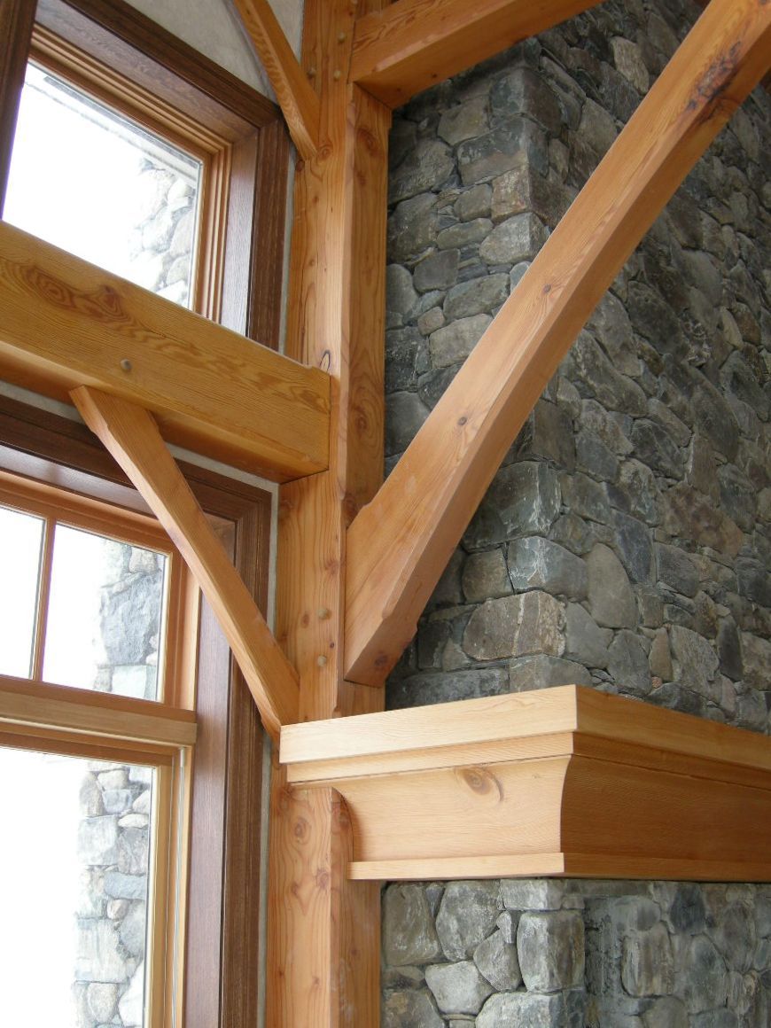 Wooden beam supports a corner with stone fireplace and windows.