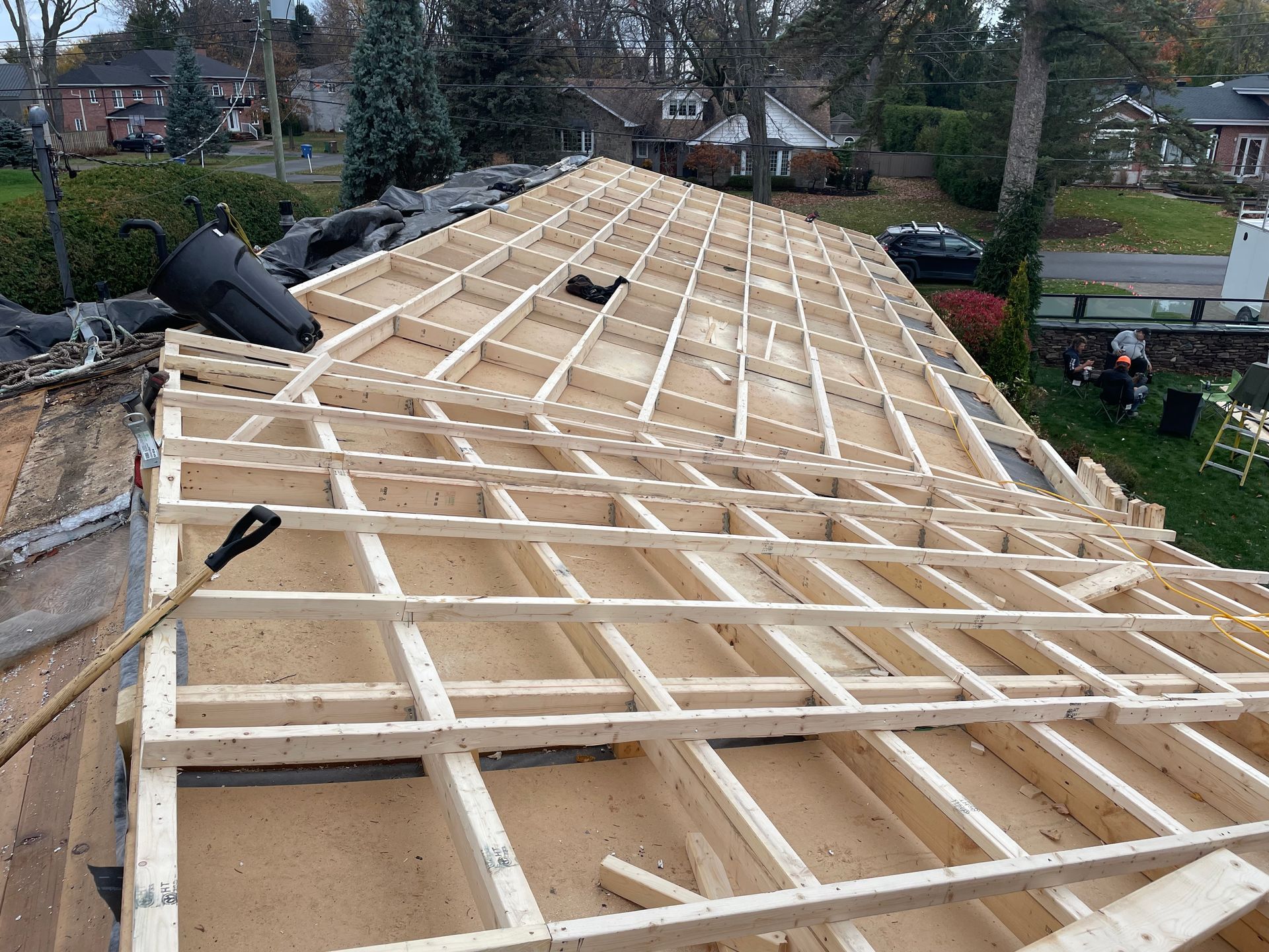 Roof under construction, wooden frame exposed, with a shovel and debris.