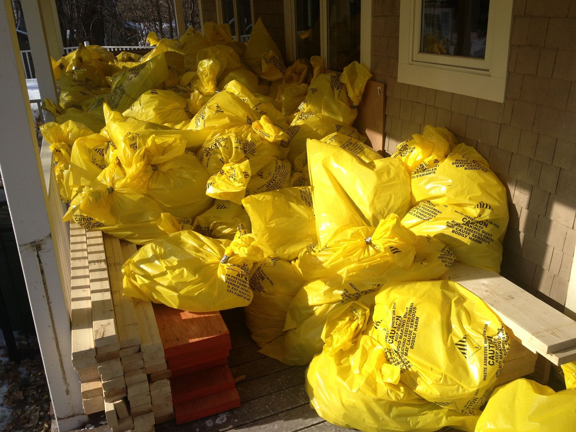 Yellow bags of debris stacked on a porch, likely for disposal.