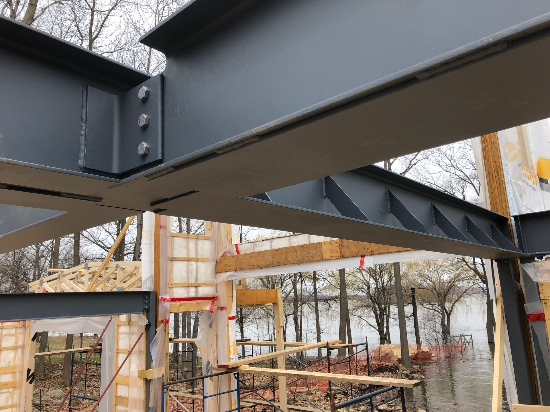 Steel beams and wood framing under construction, near a body of water.