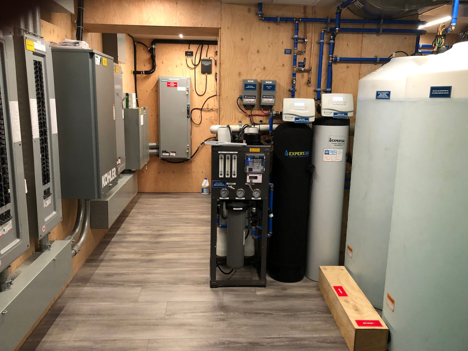 Water filtration system in a utility room with tanks, pipes, and control panels.