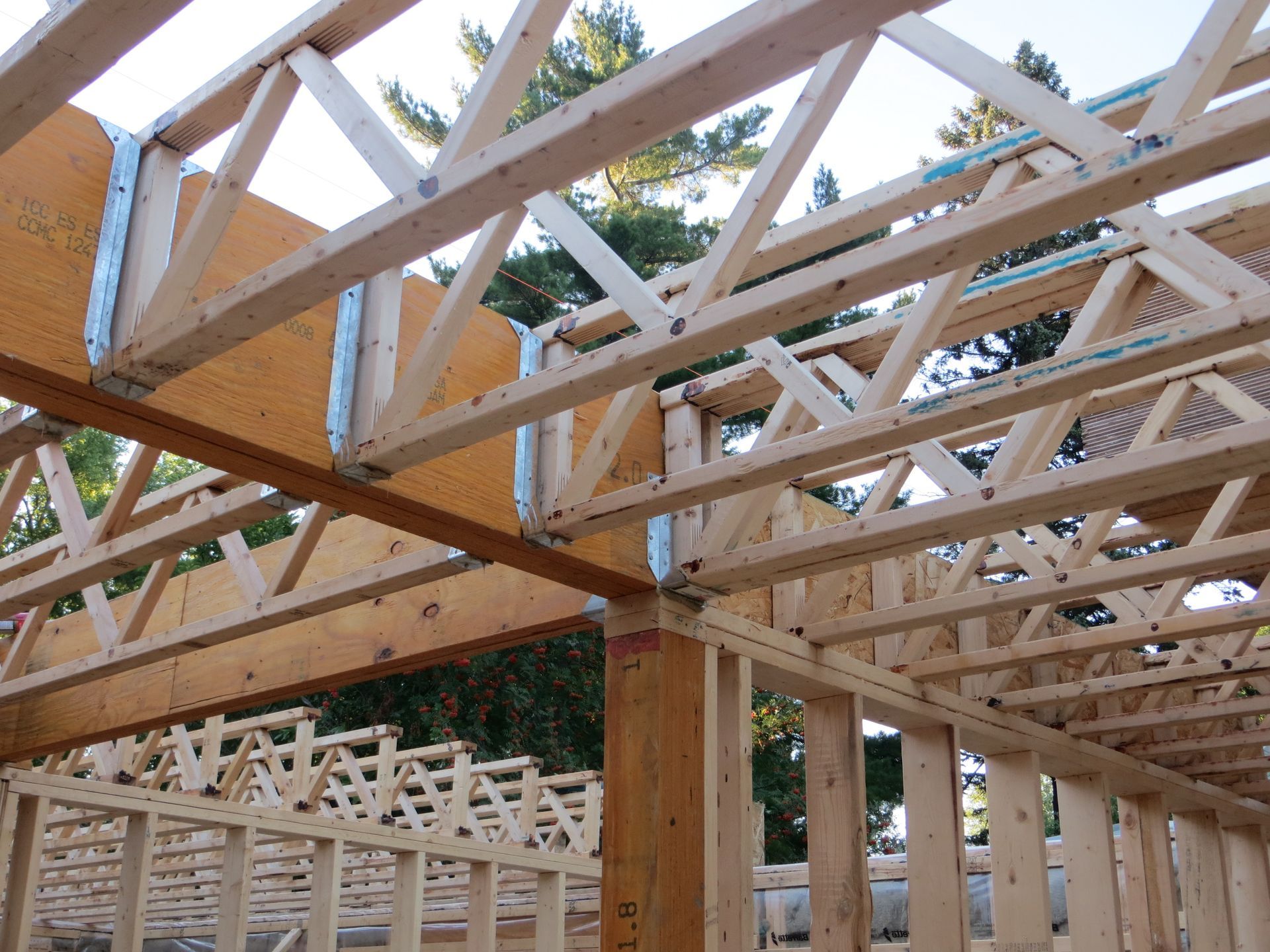Wooden house frame under construction, featuring trusses and beams.
