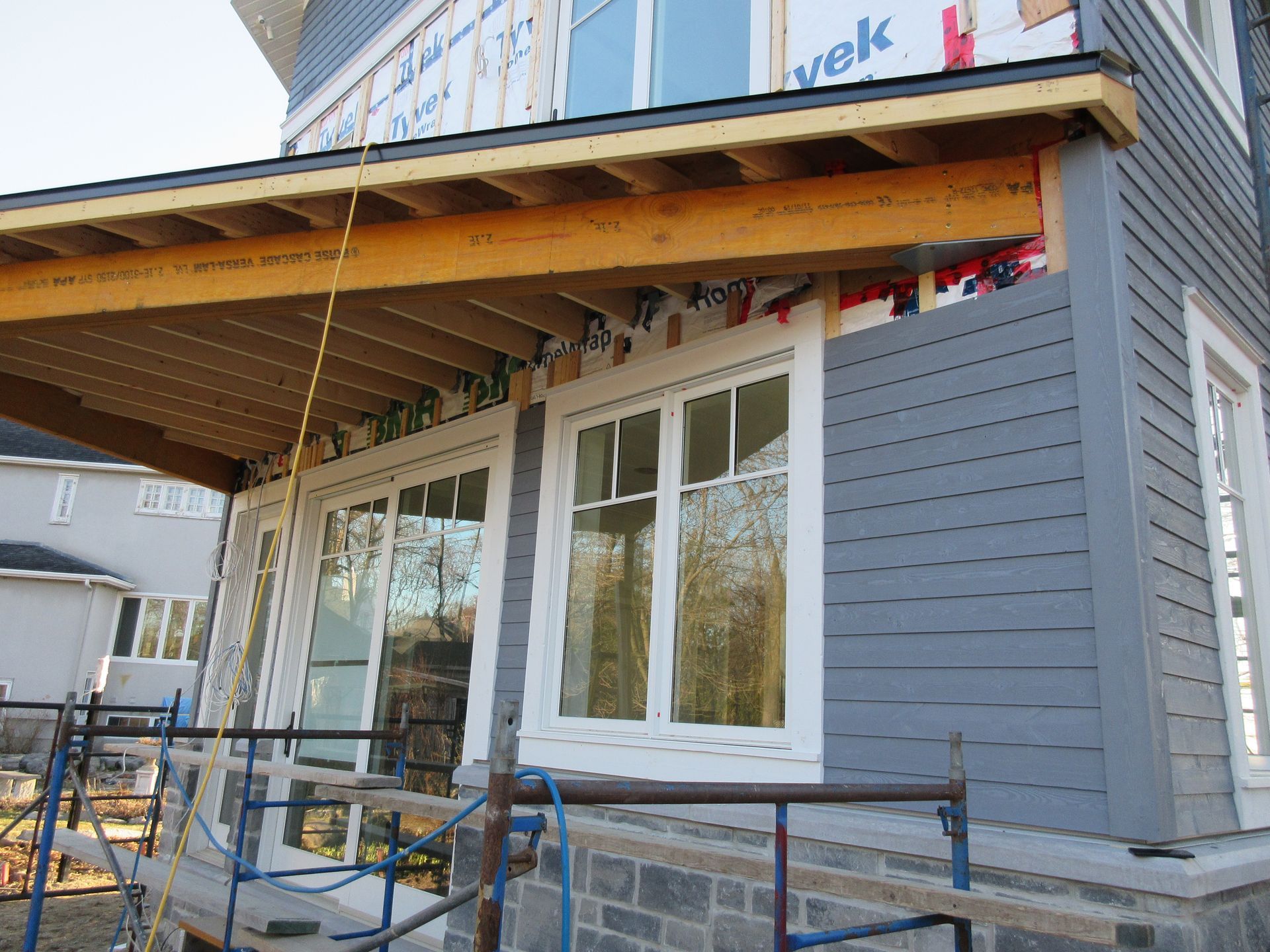 House exterior under construction, with windows, siding, and exposed wooden framing.