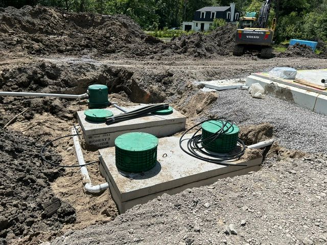 Two concrete septic tanks with green lids under construction.