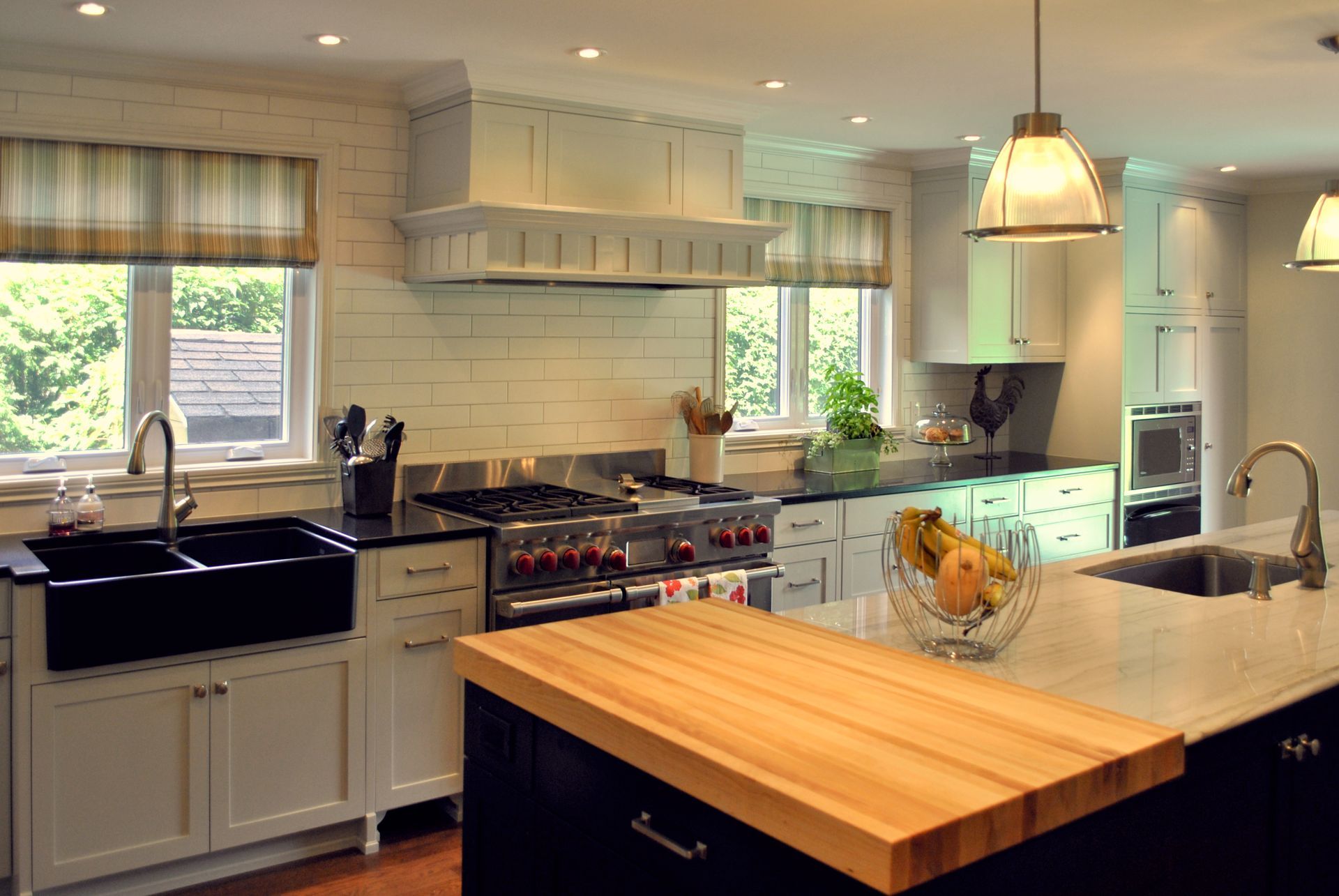 Kitchen with white cabinets, black countertops, stainless steel appliances, and a butcher block island.
