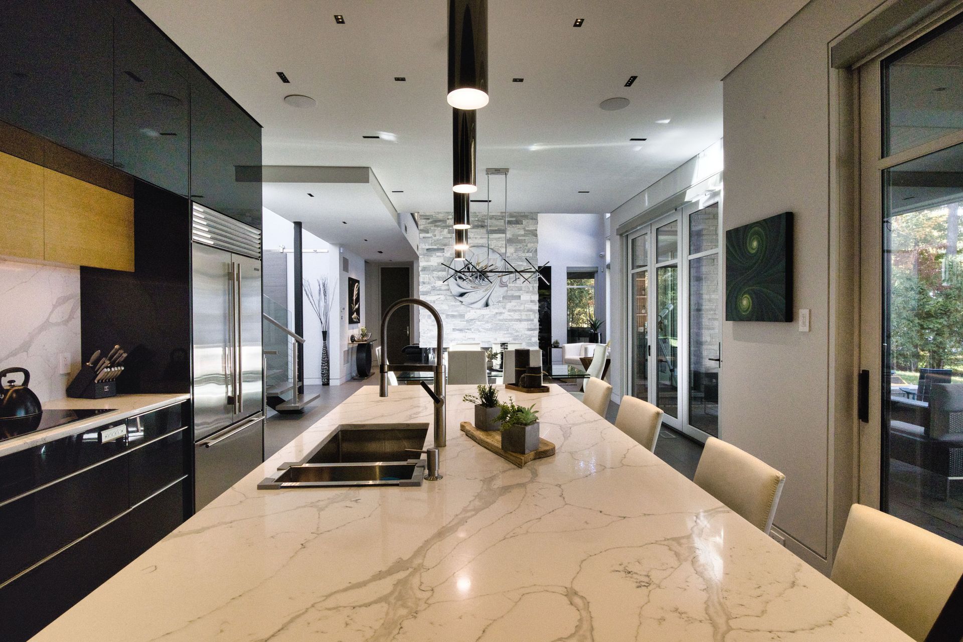 Modern kitchen with a long marble island, black cabinets, and outdoor access.