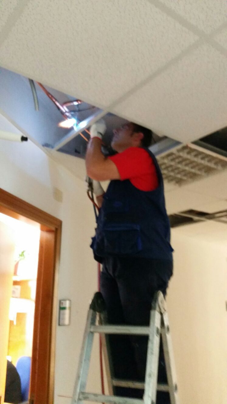 un uomo su una scala al lavoro con dei cavi su un soffitto