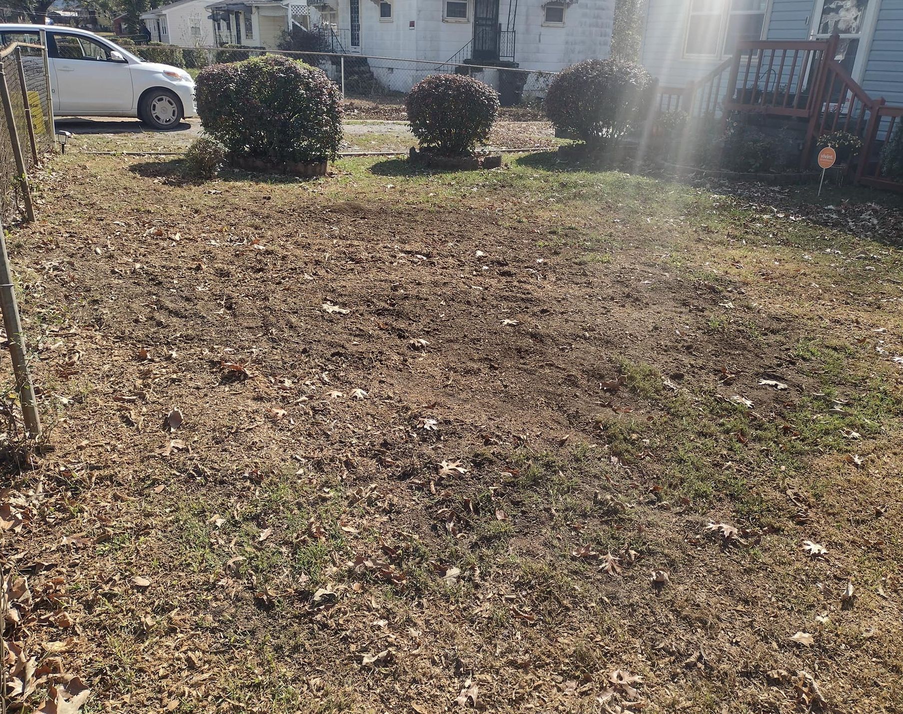A white car is parked in the backyard of a house.