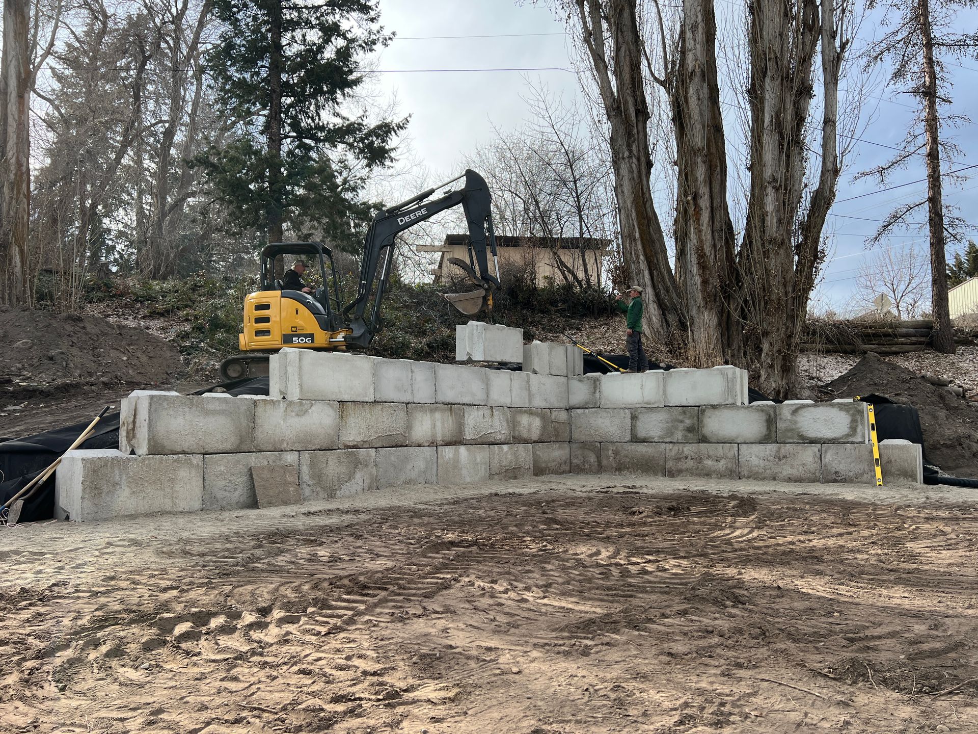 A yellow excavator is sitting on top of a pile of concrete blocks.
