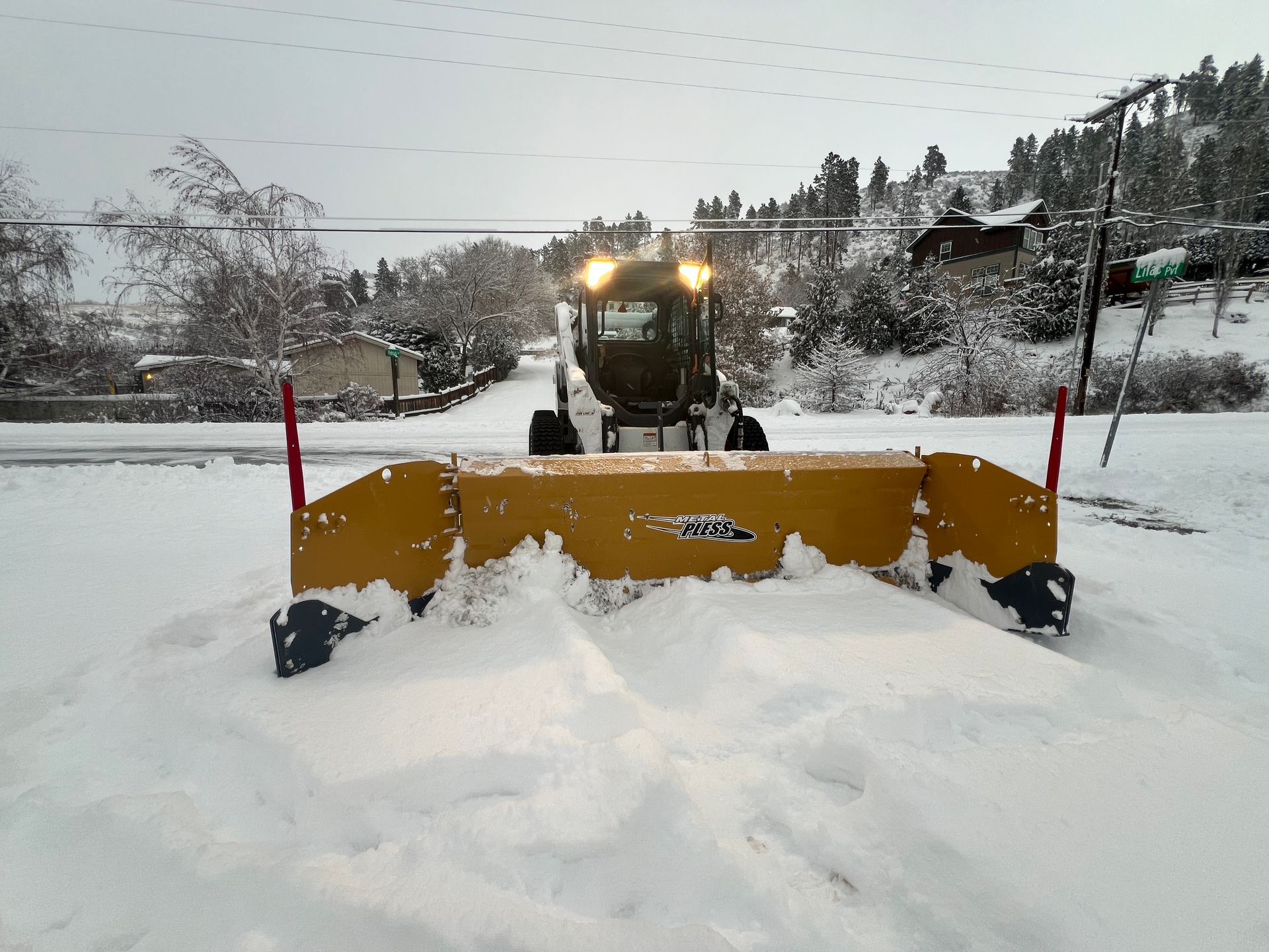 A snow plow is driving down a snowy road
