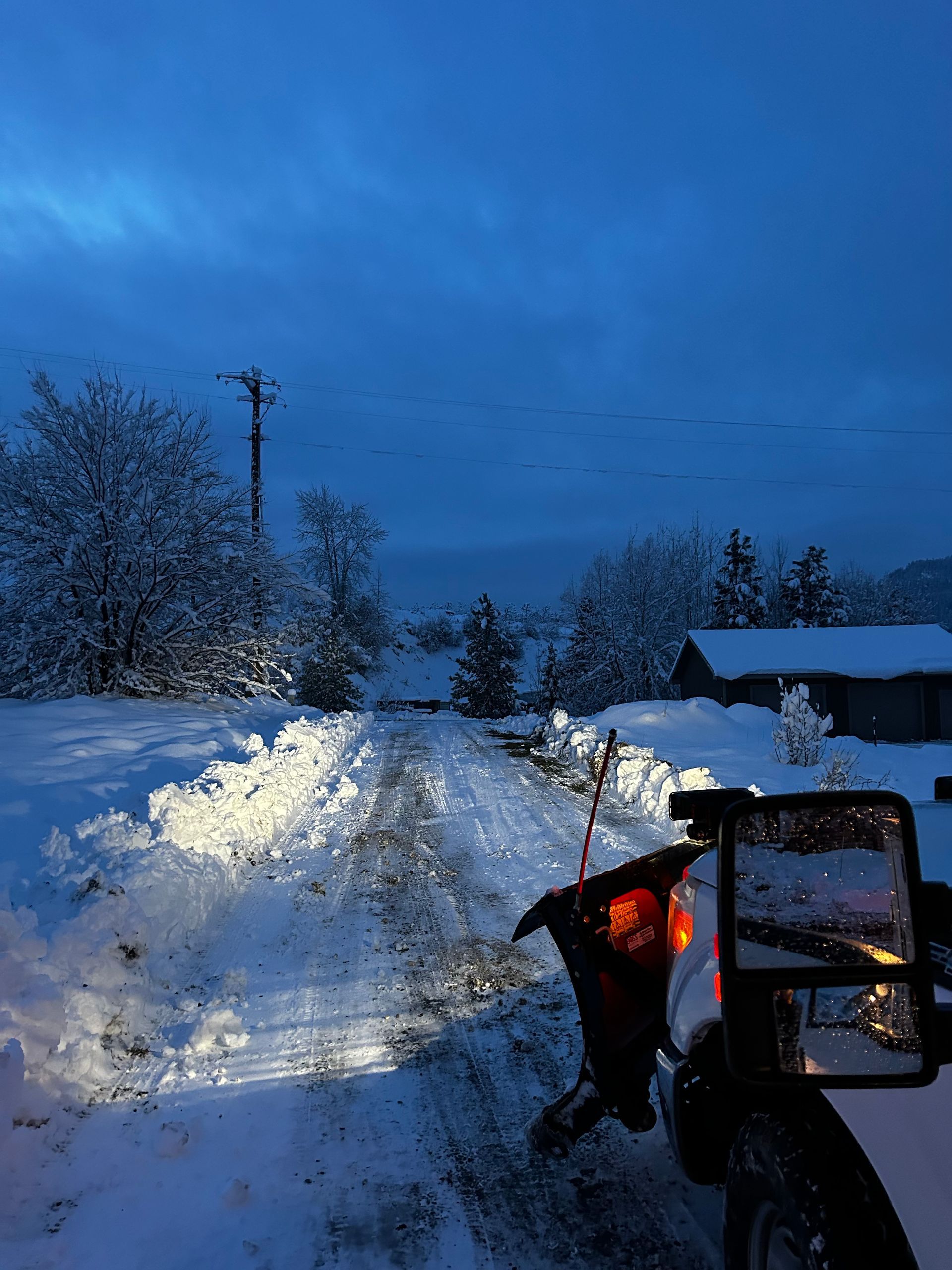 A snow plow is sitting on the side of a snow covered road.