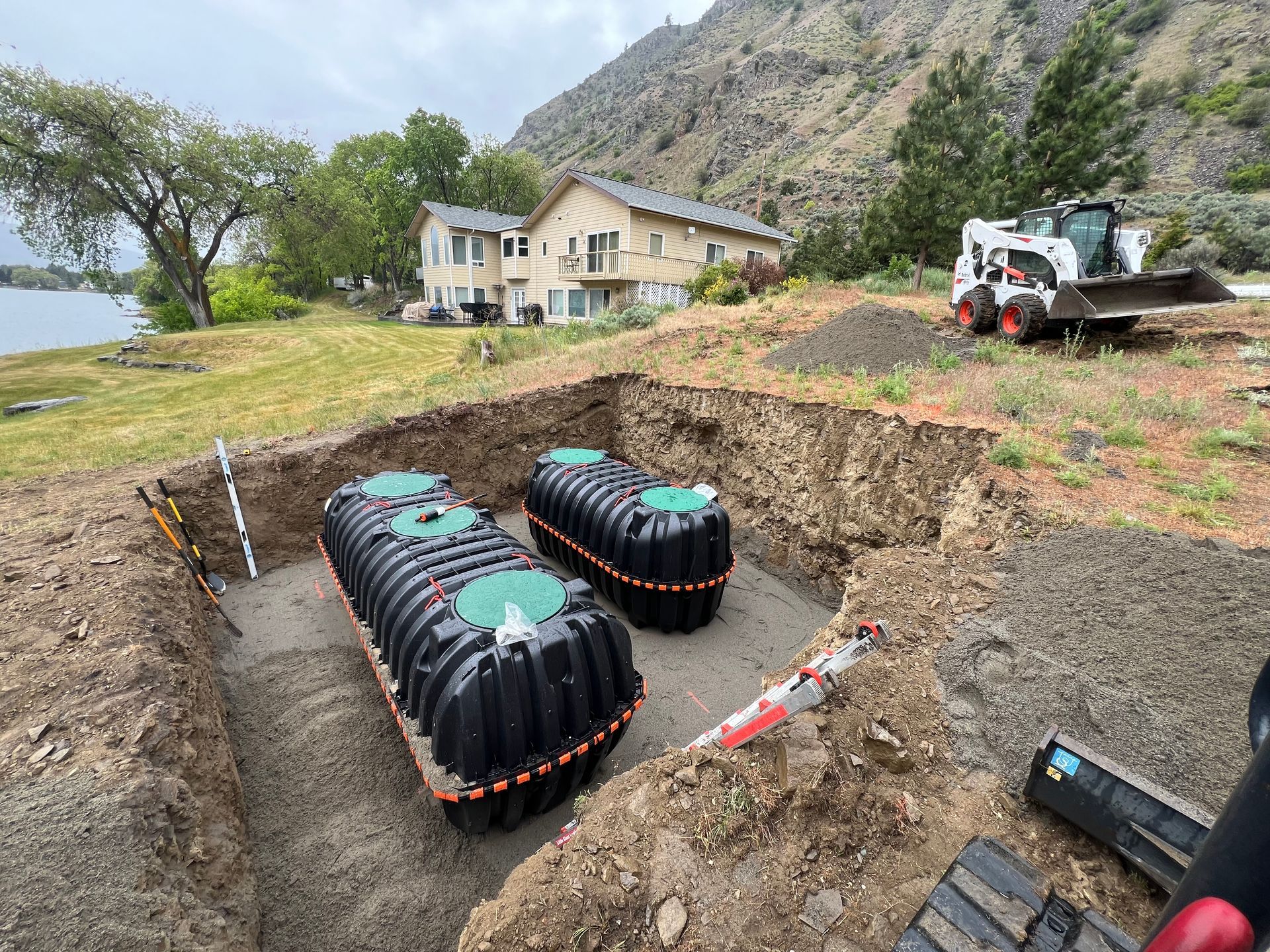 Two septic tanks are being installed in a hole in the ground.