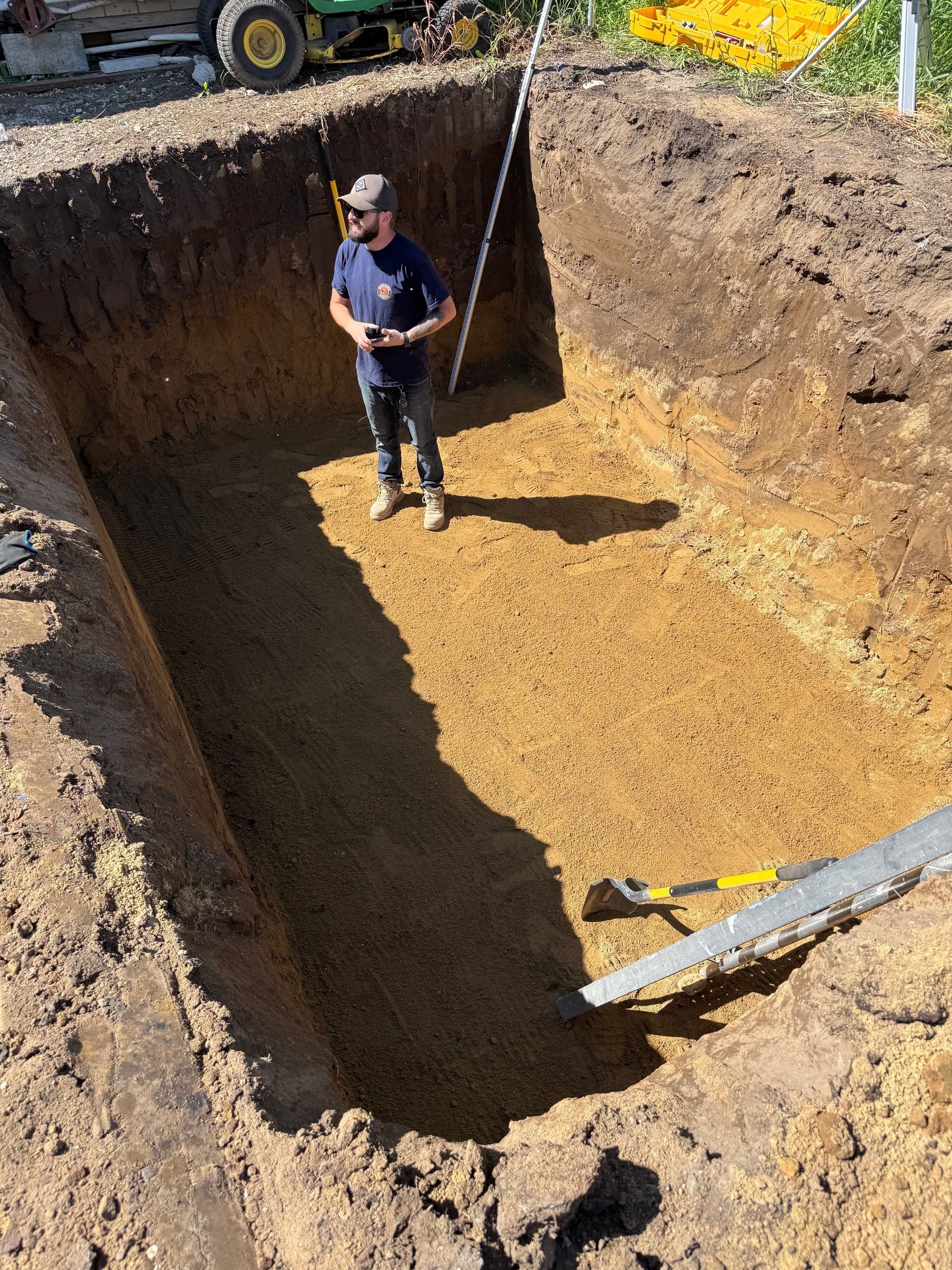 A man is standing in a large hole in the ground.