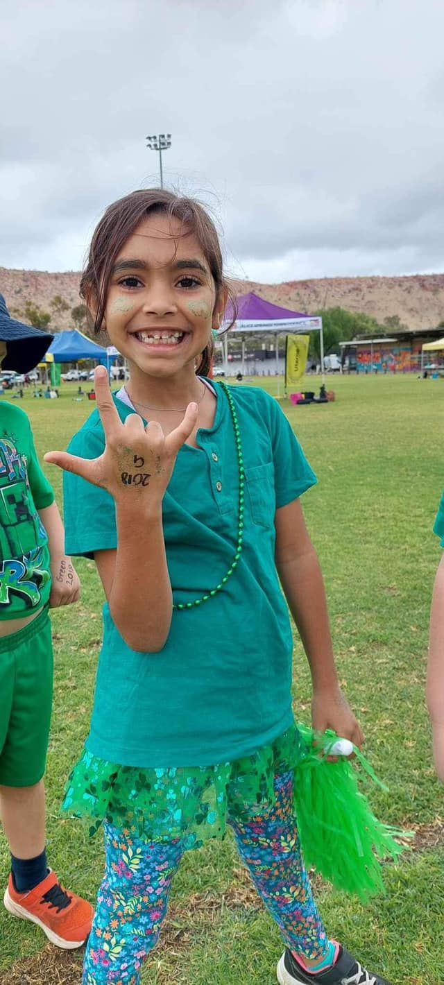 Young girl smiling, wearing green, gesturing 