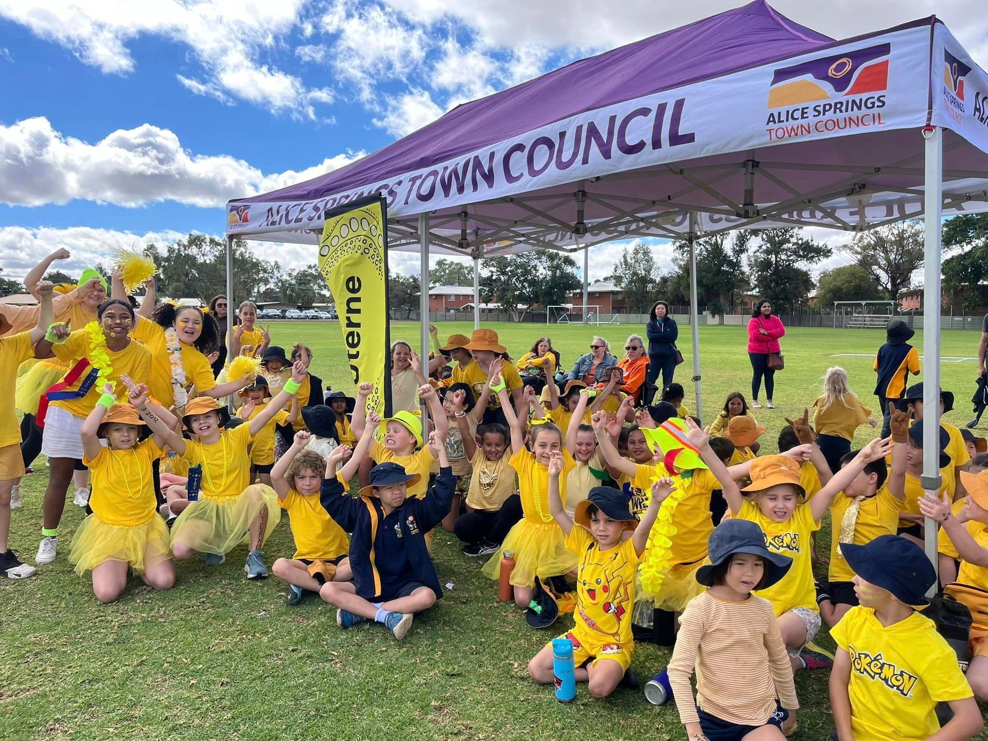 Children in yellow outfits celebrating under a tent with 