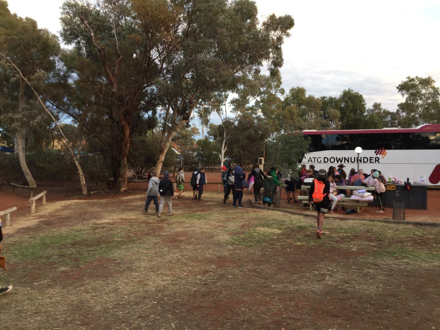 People gathered outdoors near a bus that says 